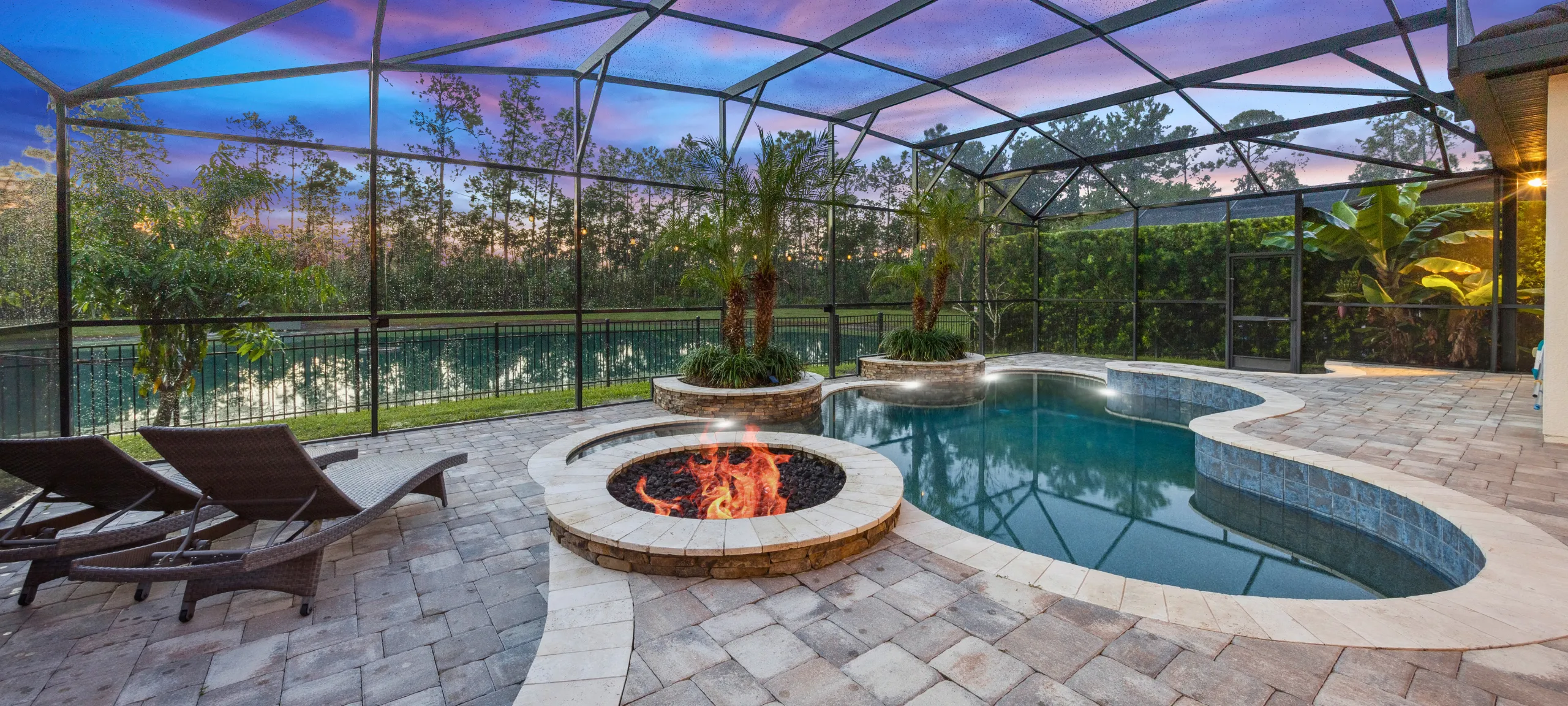 Windermere Home screen lanai with pool and firepit facing a pond with fountain at sunrise